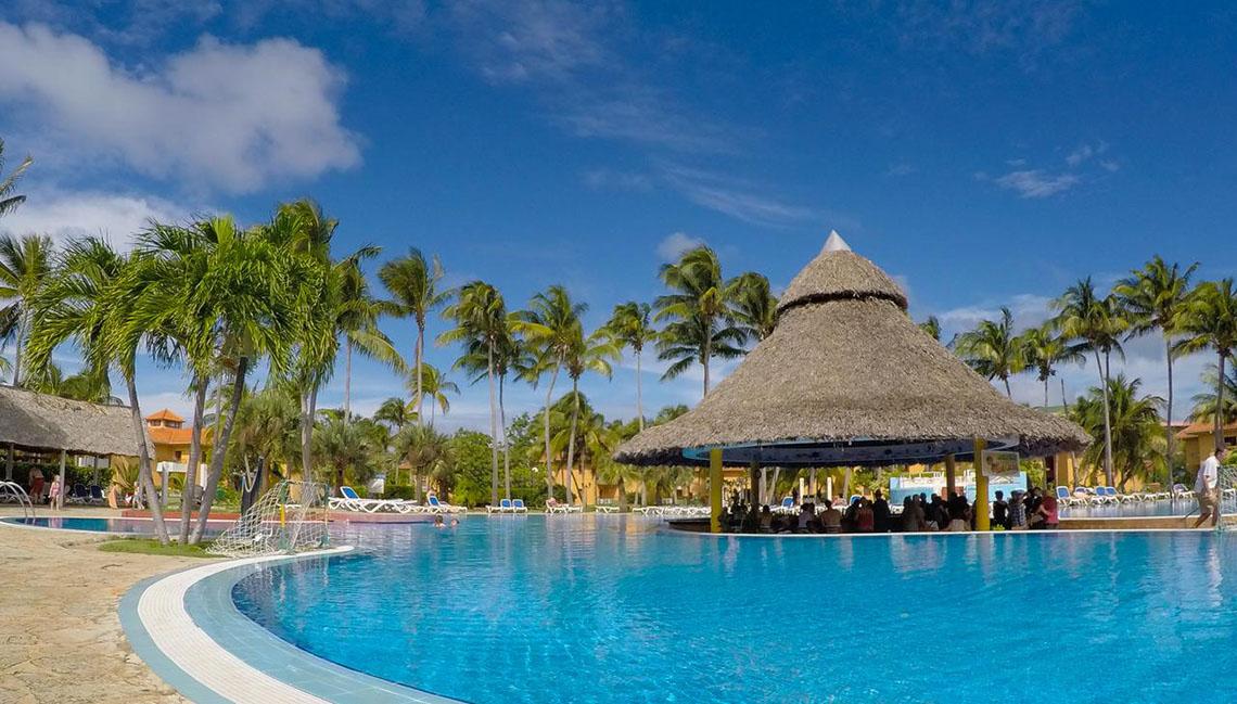 Poolbar im ROC Arenas Doradas Hotel mit Strohdach und Palmen im Hintergrund.