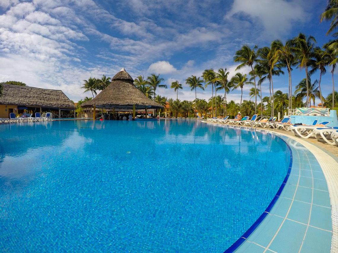 Außenpool des ROC Arenas Doradas Hotels mit Lounge-Stuhlreihen und Palmen.