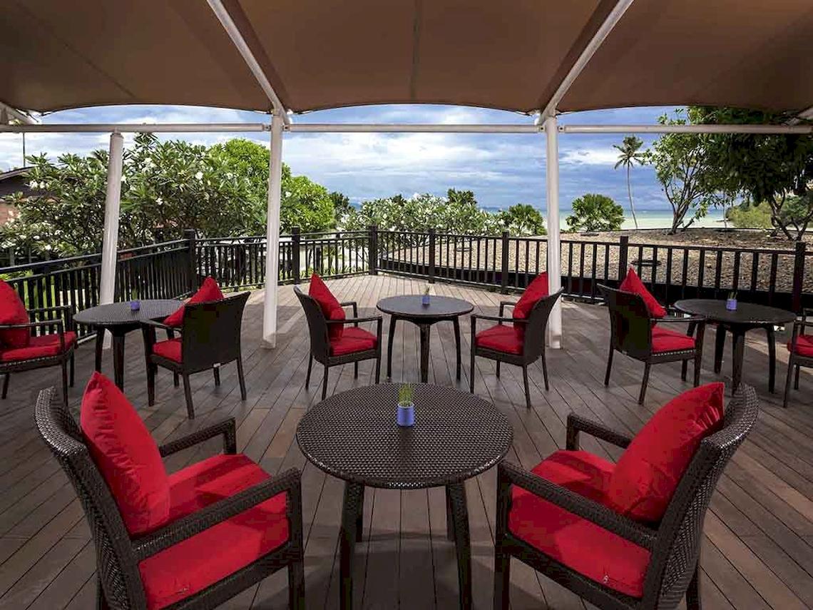 Ausblick von der Terrasse des Pullman Phuket Panwa Beach Resort mit roten Kissen und Tischen.