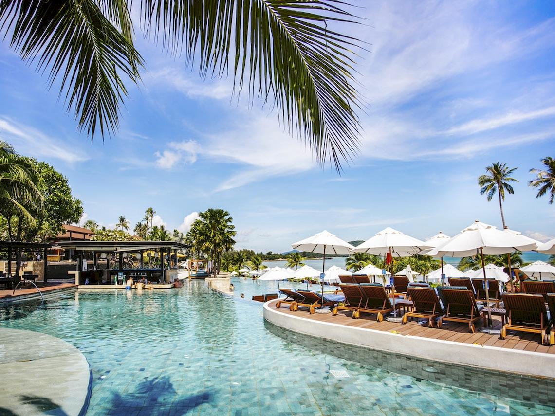 Poolbereich des Pullman Phuket Panwa Beach Resort mit Sonnenliegen und Schirmen
