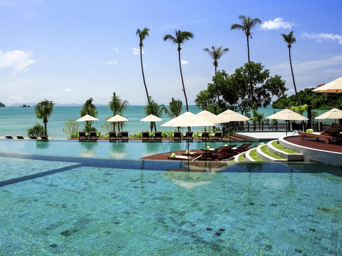 Poolbereich des Pullman Phuket Panwa Beach Resort mit Blick auf das Meer und Palmen