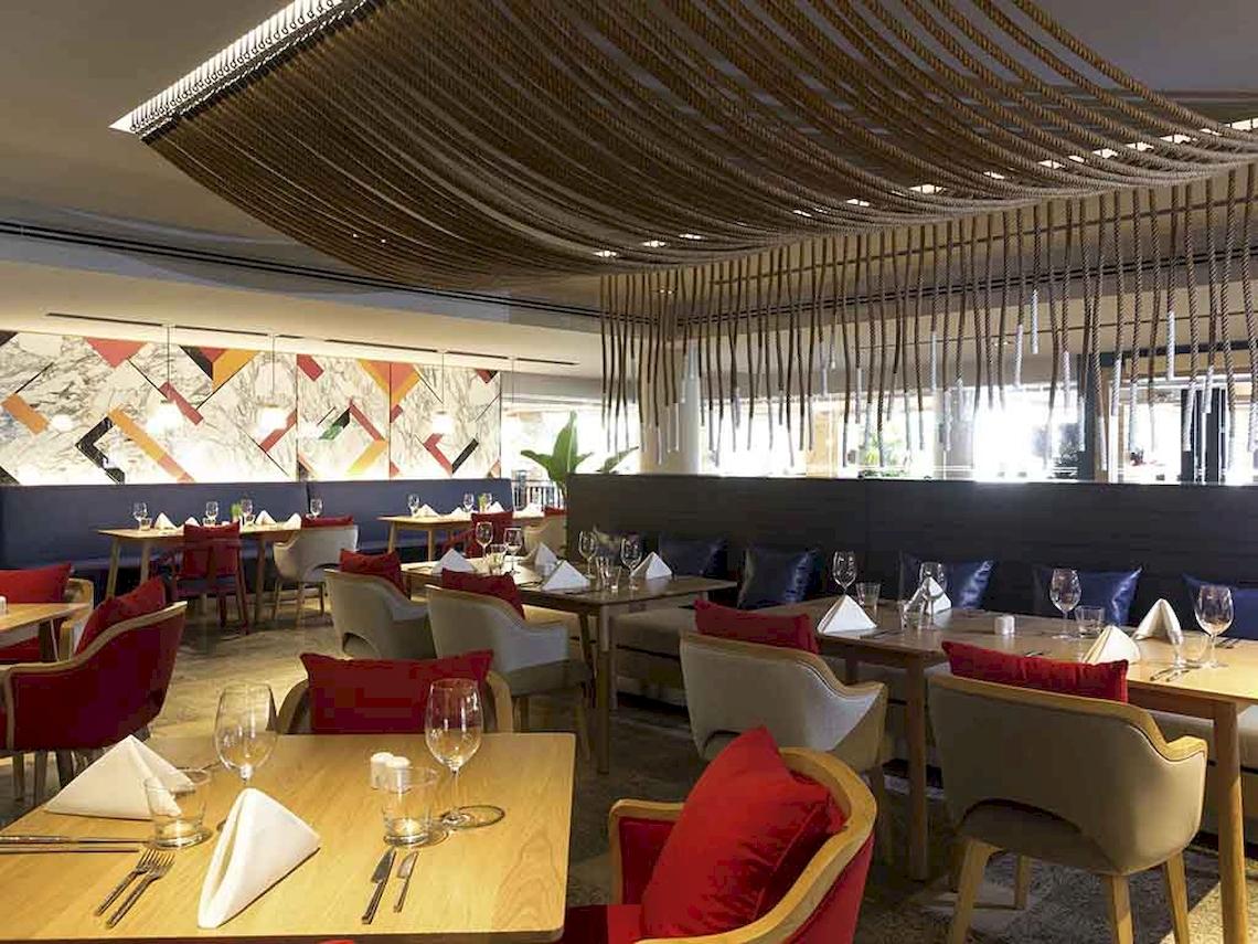 Innenansicht des Restaurants im Pullman Phuket Panwa Beach Resort mit eingerichteten Tischen und Stühlen.