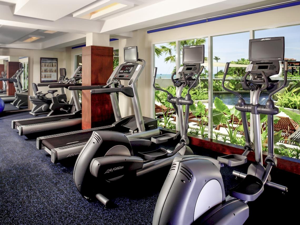 Fitnesscenter im Pullman Phuket Panwa Beach Resort mit mehreren Laufbändern und Blick auf einen See.