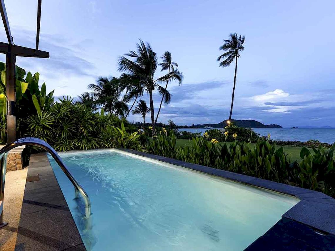 Außenpool des Pullman Phuket Panwa Beach Resorts bei Nacht mit Blick auf den Ozean und Palmen.