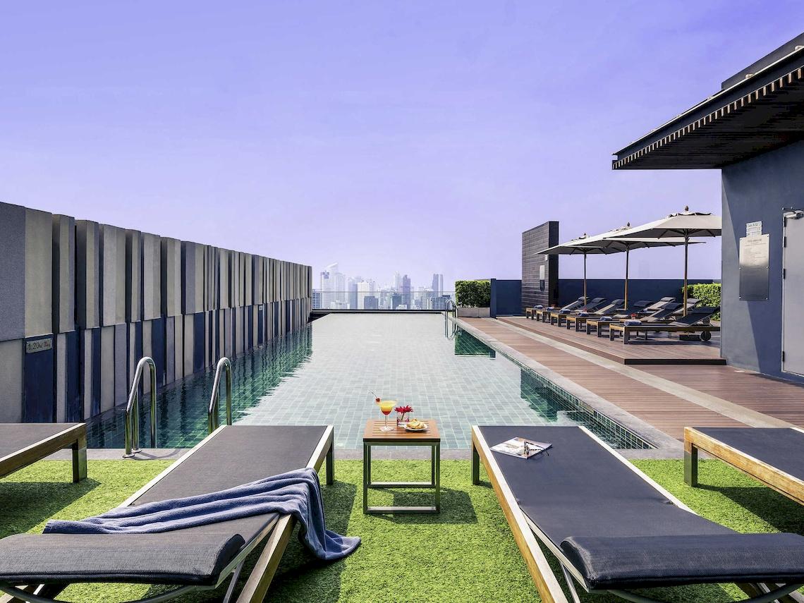 Dachterrasse des Mercure Bangkok Siam Hotels mit Pool, Lounge-Stühlen und Blick auf die Stadt.