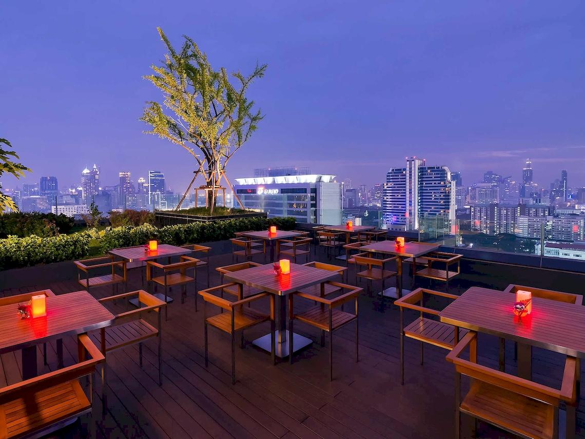 Beleuchtete Dachterrasse mit Tischen und Stühlen im Mercure Bangkok Siam Hotel