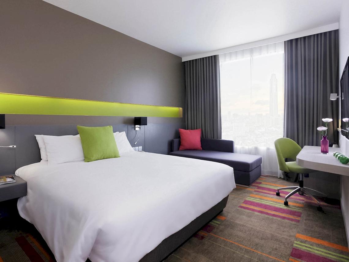 Hotelzimmer im Mercure Bangkok Siam mit Bett, Sofa, Schreibtisch und Stadtblick