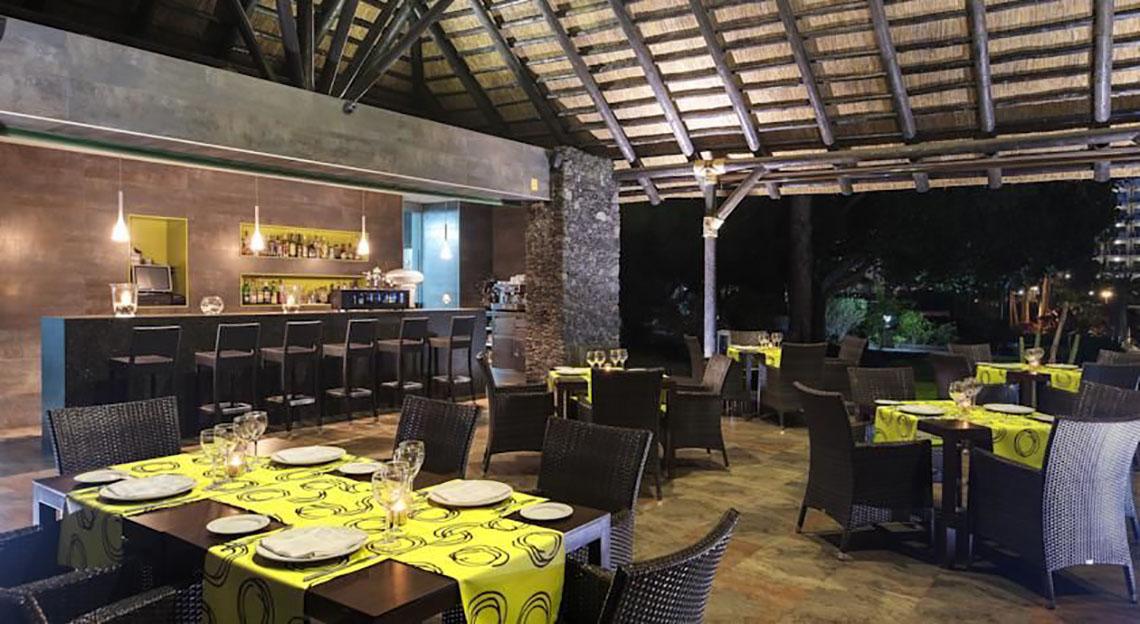 Innenbereich des Restaurants im Barcelo Margaritas Hotel mit Tischen und Stühlen, einer Bar und einer Decke.