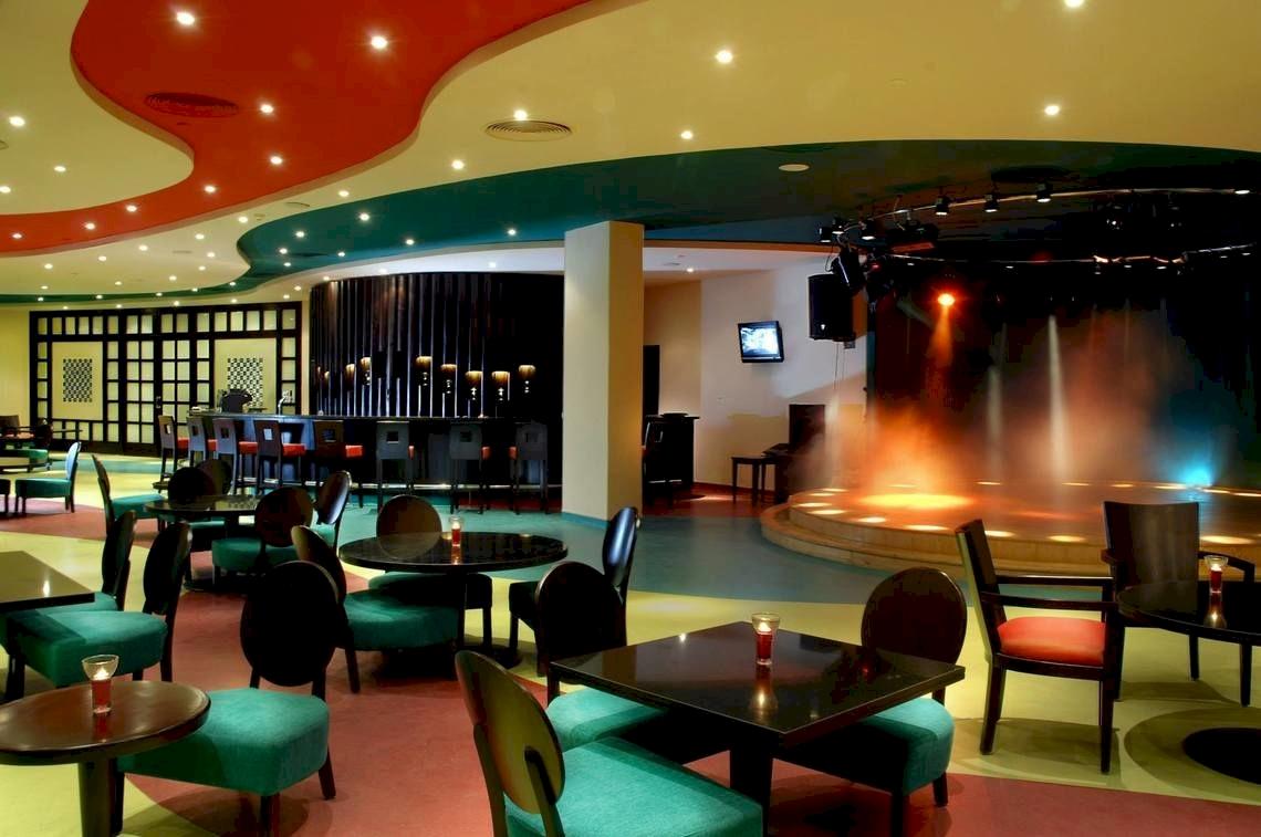 Hotellounge des DoubleTree by Hilton Sharks Bay Resort mit Tischen, Stühlen und Bühne.