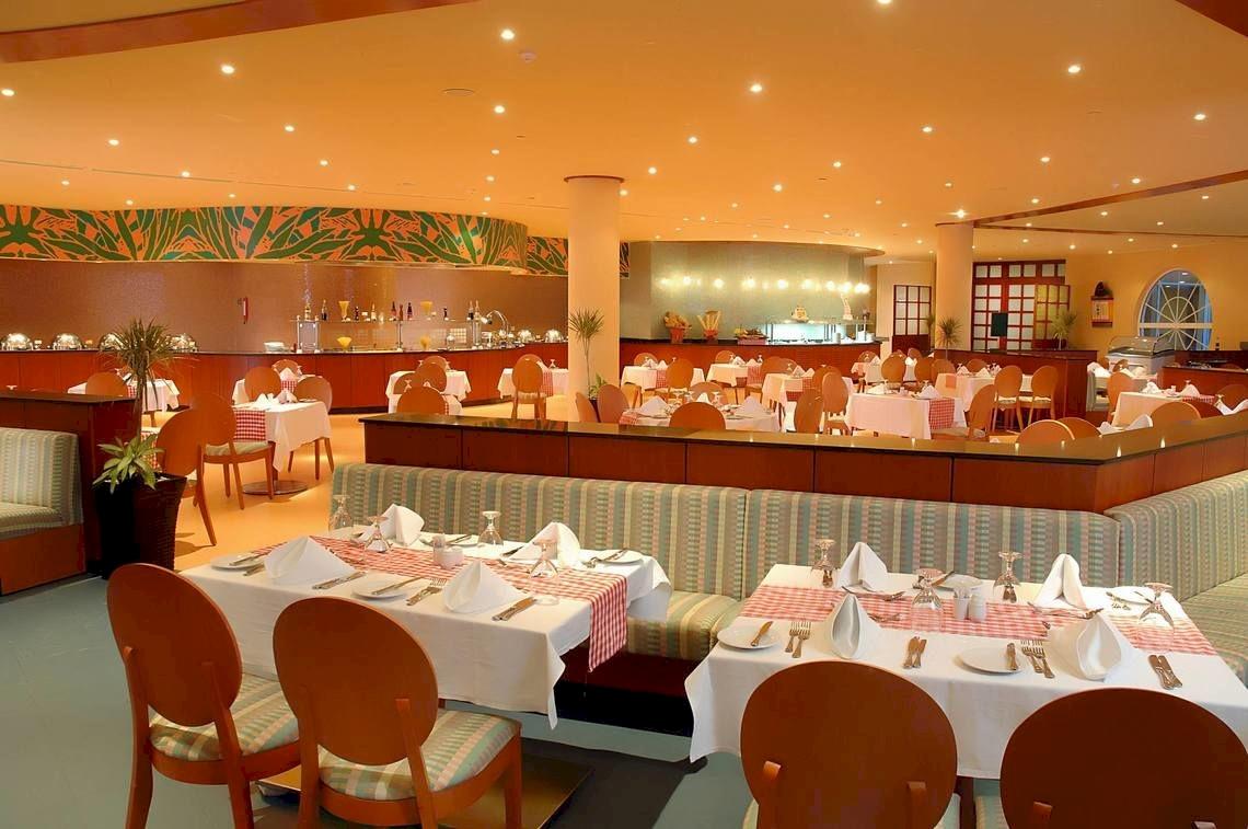 Innenansicht des Restaurants im DoubleTree by Hilton Sharks Bay Resort mit gedeckten Tischen und Stühlen.