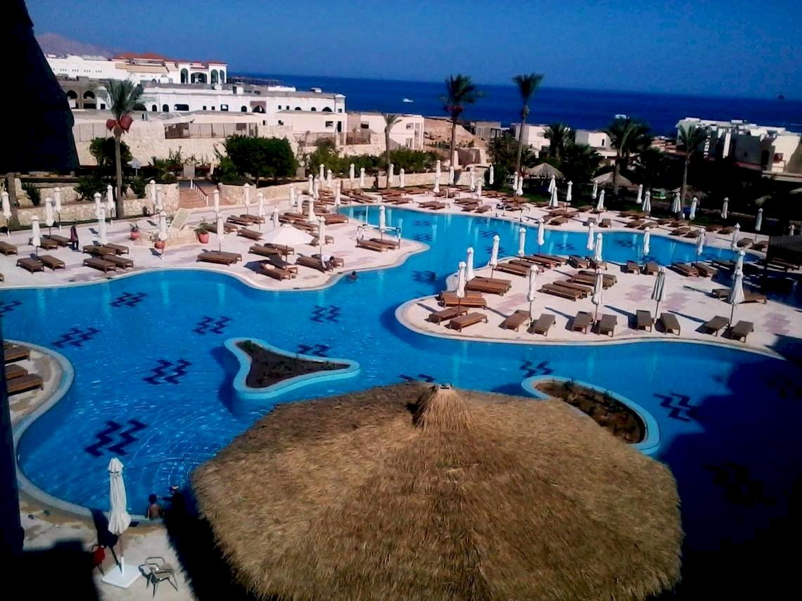 Luftaufnahme des Swimmingpools im DoubleTree by Hilton Sharks Bay Resort mit vielen Sonnenliegen und Schirmen