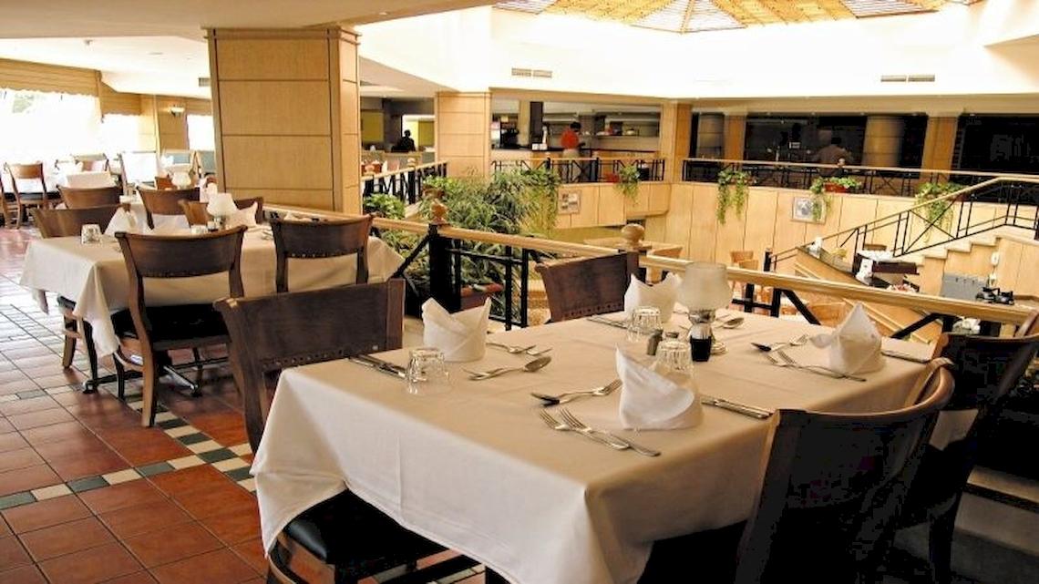 Innenansicht des Restaurants im DoubleTree by Hilton Sharks Bay Resort mit gedeckten Tischen und Stühlen.