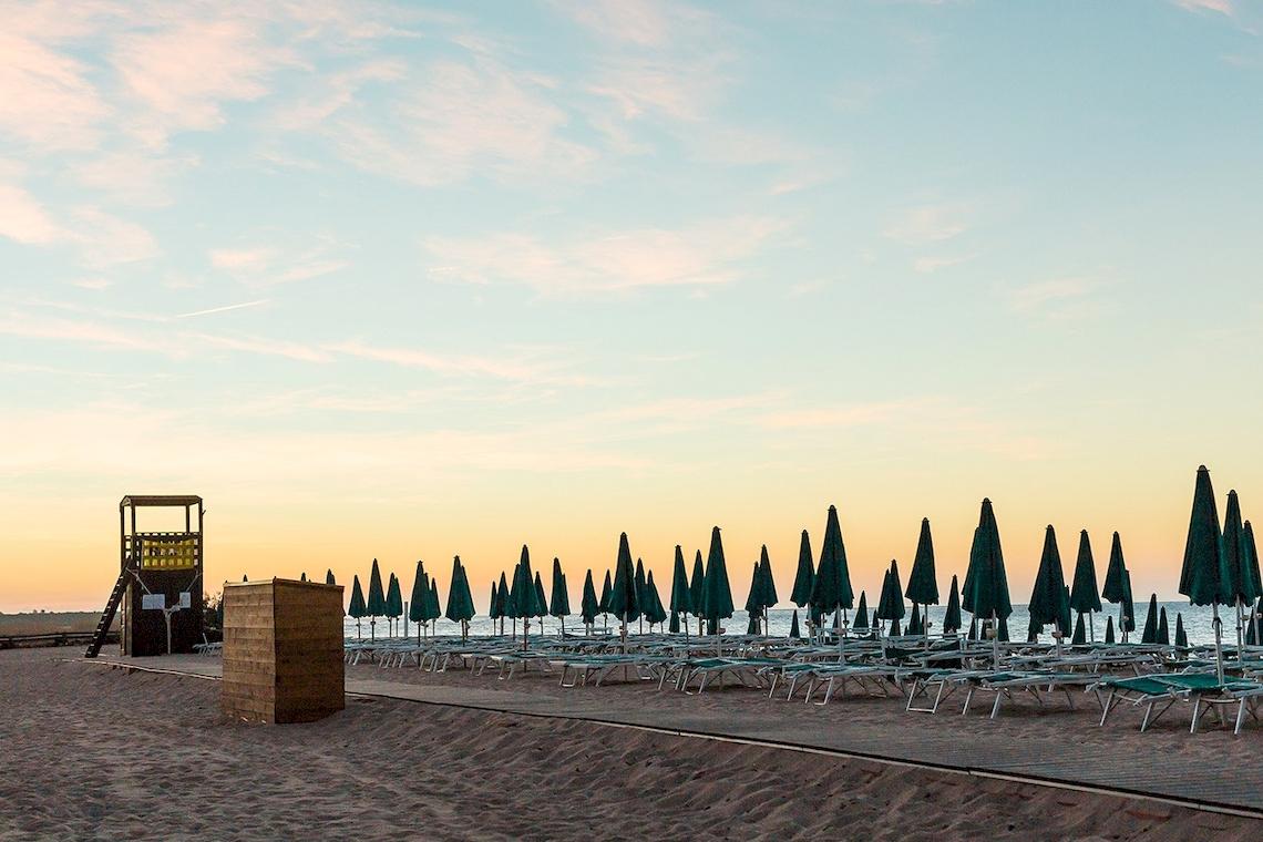Strandszene mit Sonnenliegen und grünen Sonnenschirmen vor dem Club Hotel Marina Beach.
