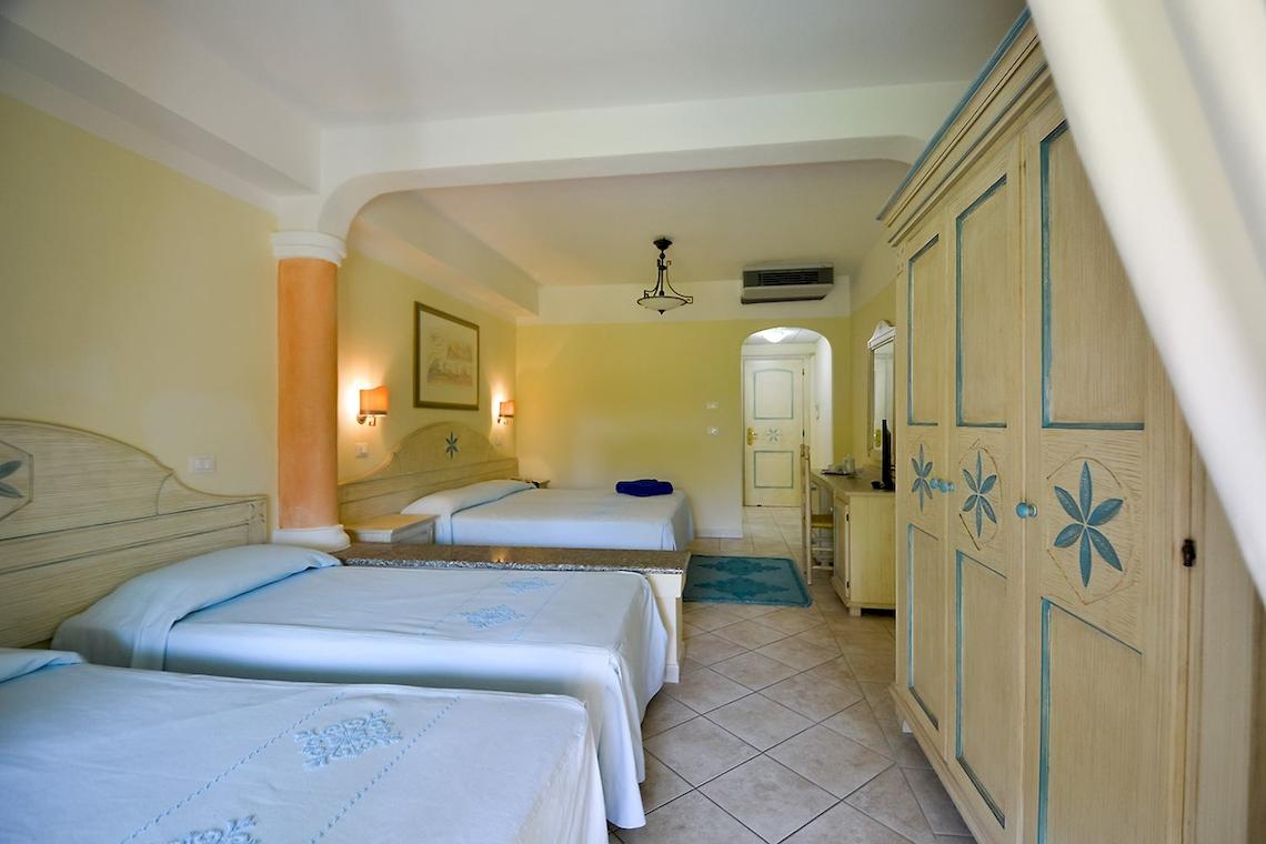 Schlafzimmer im Club Hotel Marina Beach mit drei Betten und gelben Wänden.