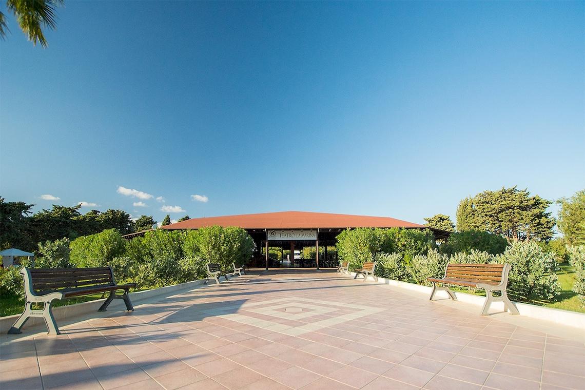 Eingangsbereich des Club Hotel Marina Beach mit Bänken und grünen Büschen