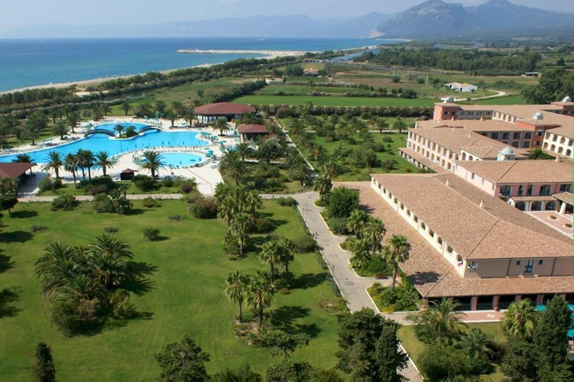 Außenansicht des Club Hotel Marina Beach Resorts mit Swimmingpool, Gebäuden und Meer im Hintergrund.