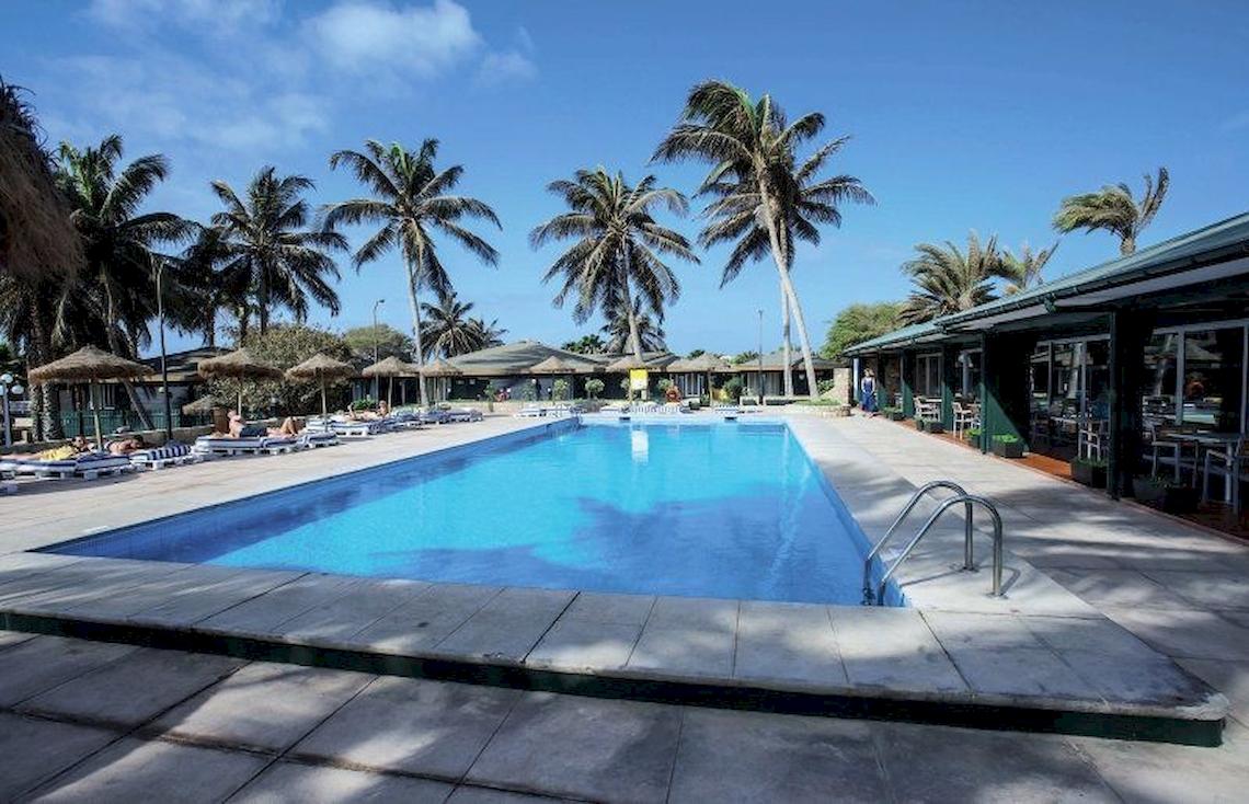 Außenpool des Oasis Belorizonte Hotels mit Liegestühlen und Palmen