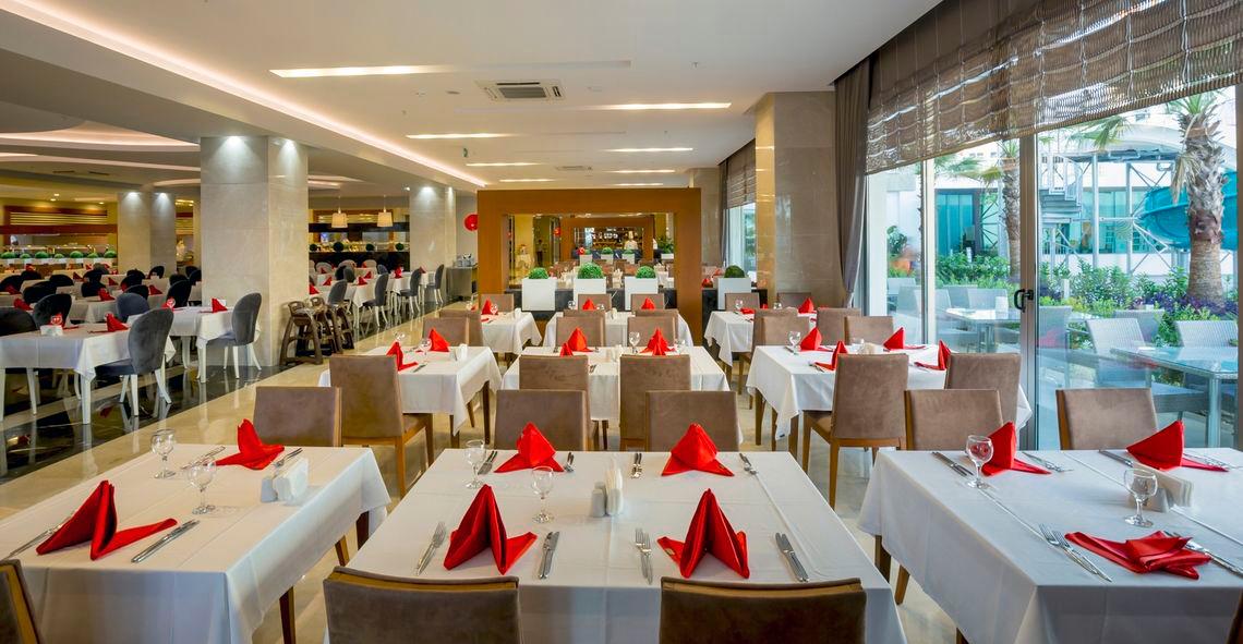 Restaurant im Side Sunport Hotel & Spa mit gedeckten Tischen und roten Servietten.