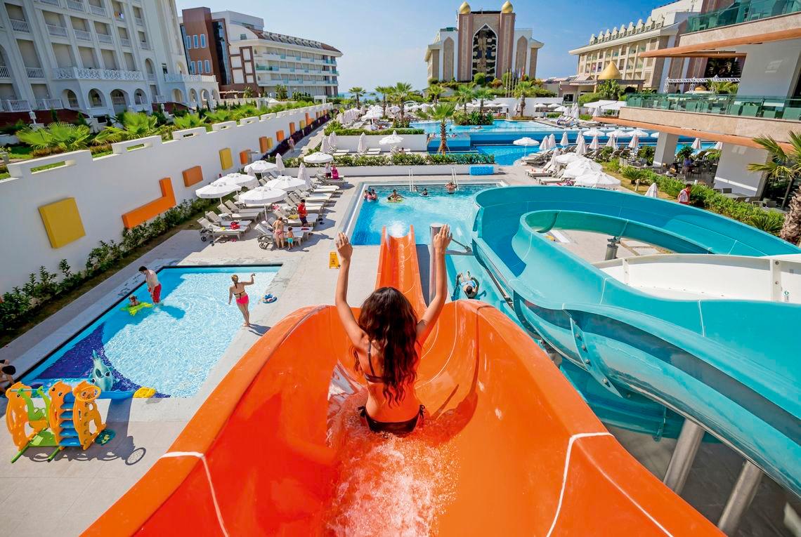 Ein Schwimmbad mit Wasserrutschen und Gästen im Side Sunport Hotel & Spa.