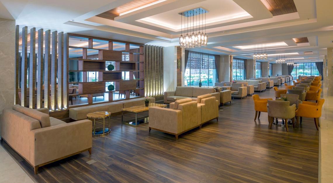 Lobby des Side Sunport Hotel & Spa mit modernen Möbeln und Holzböden.