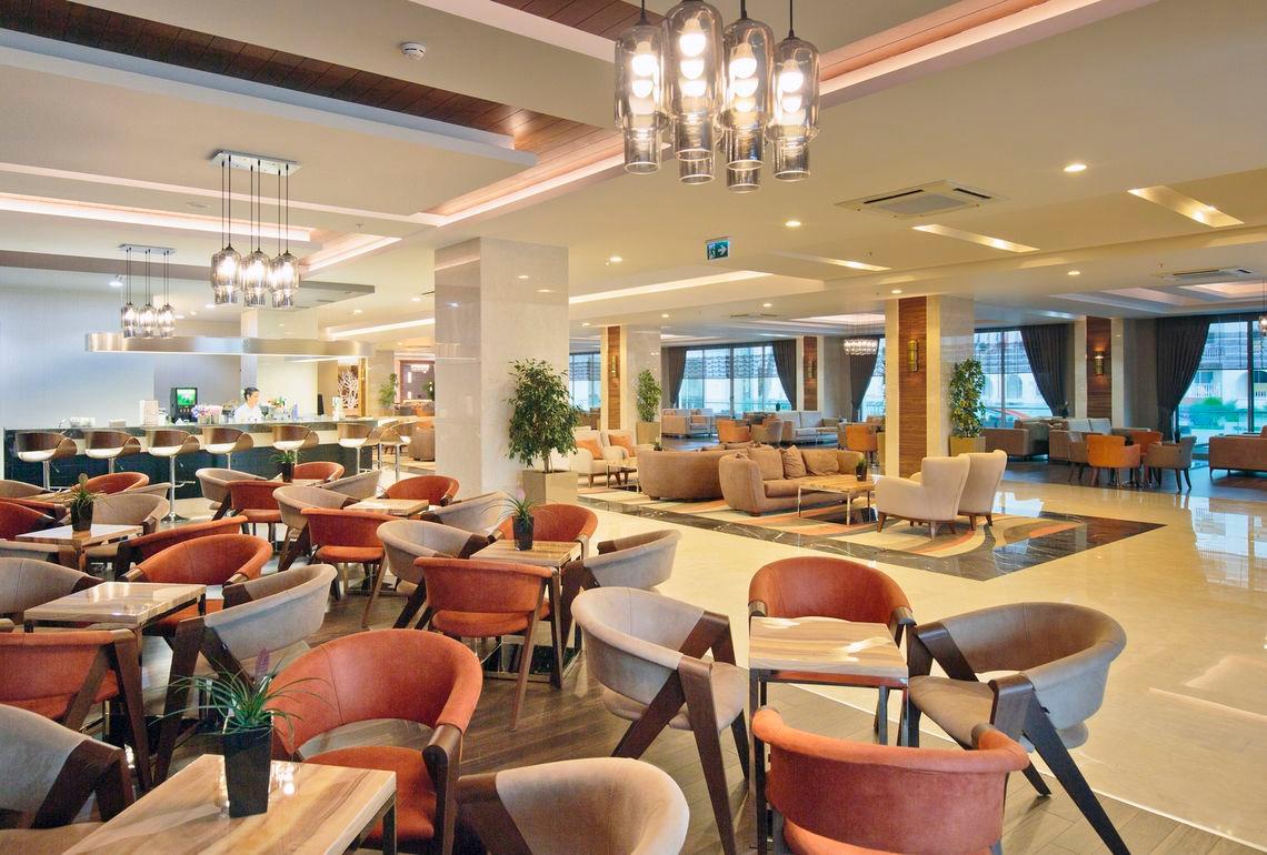 Lobby des Side Sunport Hotel & Spa mit Sitzbereichen, Tischen und Kronleuchtern