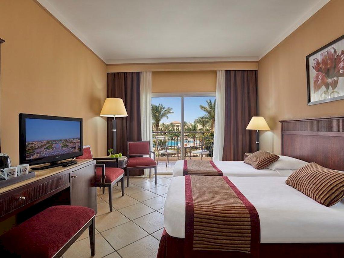 Doppelzimmer im Jaz Mirabel Beach Hotel mit zwei Betten und Fernseher.