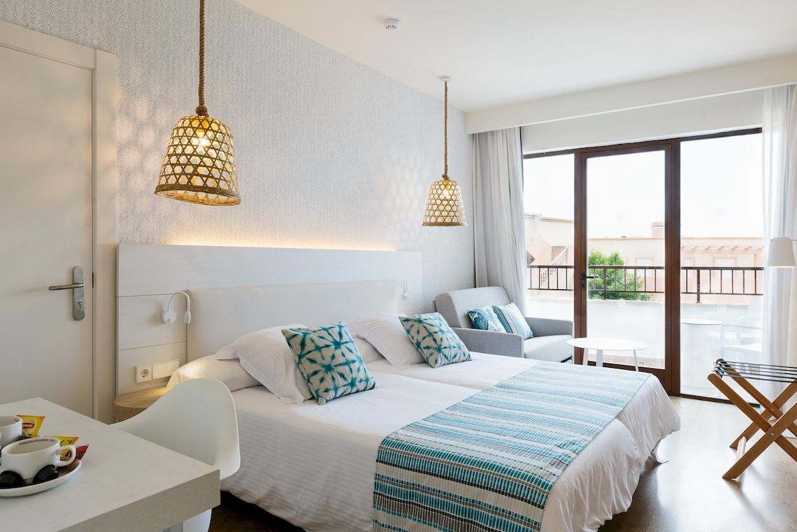 Doppelzimmer im Leonardo Royal Hotel Ibiza Santa Eulalia mit zwei Betten, Wohnzimmer und Balkon.