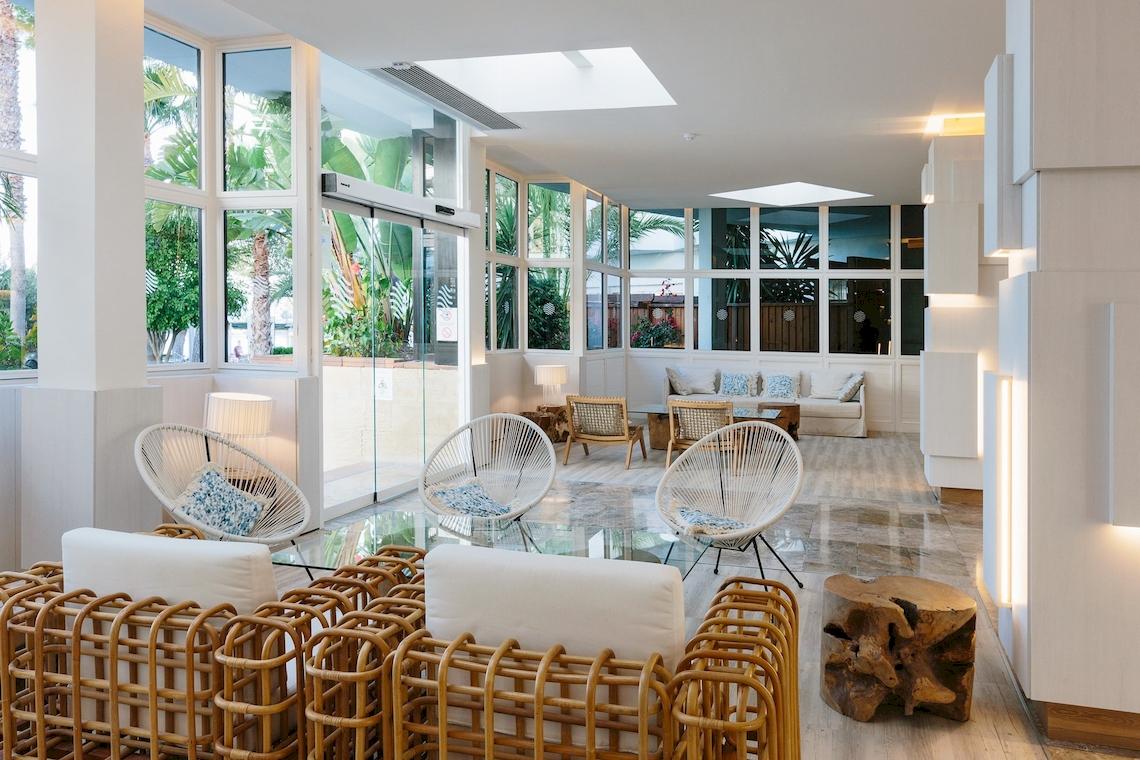 Leonardo Royal Hotel Ibiza Santa Eulalia Lobby mit weißen Möbeln und großen Fenstern.