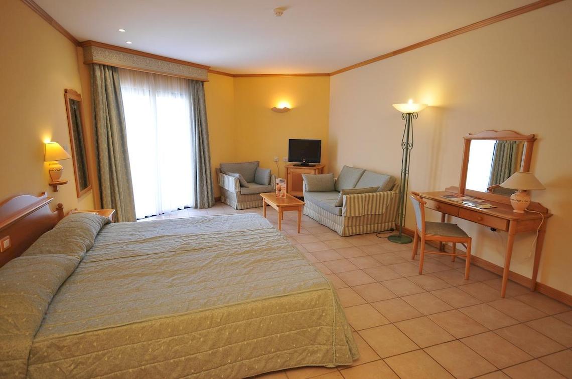 Innenansicht eines Zimmers im Grand Hotel Gozo mit Bett, Möbeln und Fernseher.