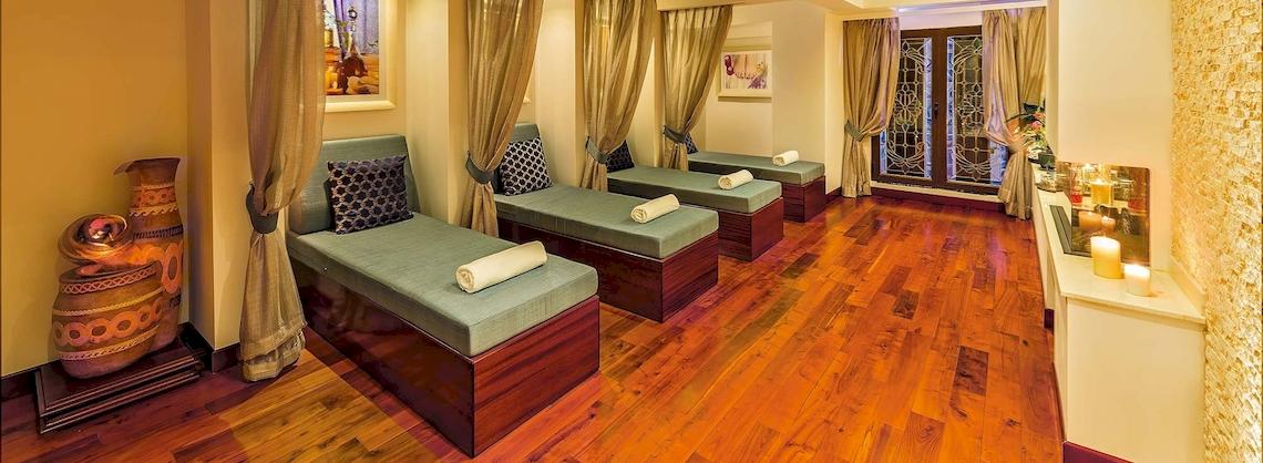 Spa-Lounge im Grand Hotel Gozo mit grünen Liegen, Holzböden und Kerzen.