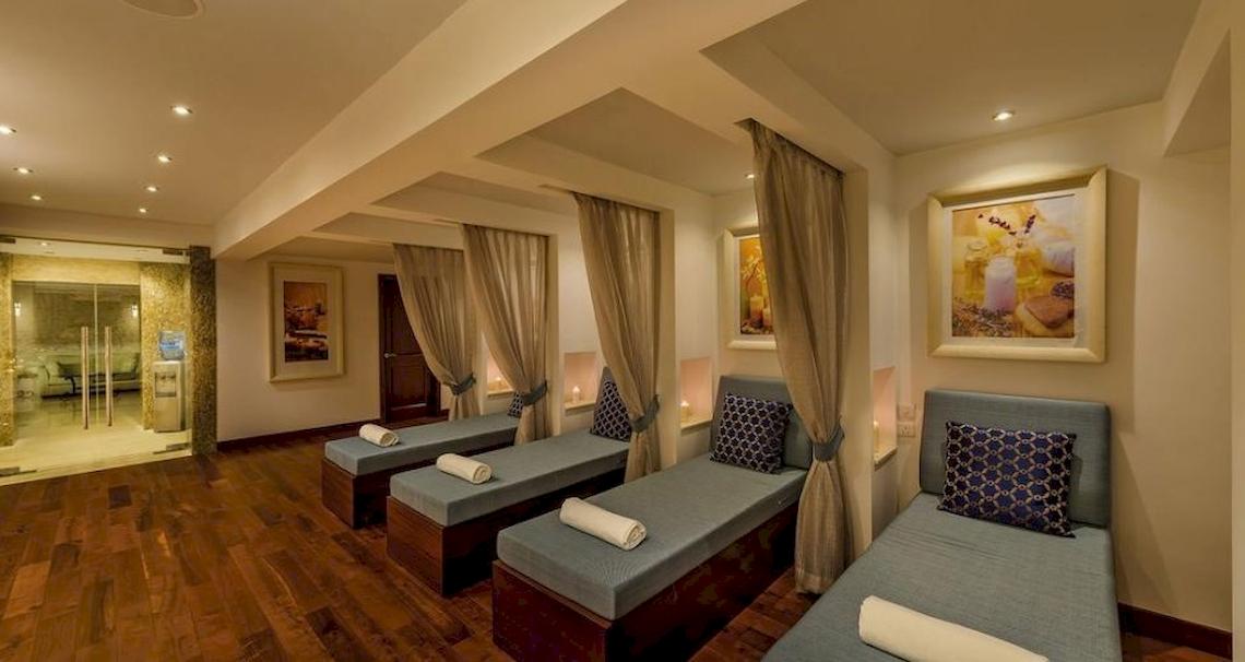 Behandlungsraum im Grand Hotel Gozo Spa mit drei Liegen, Kissen und Vorhängen.