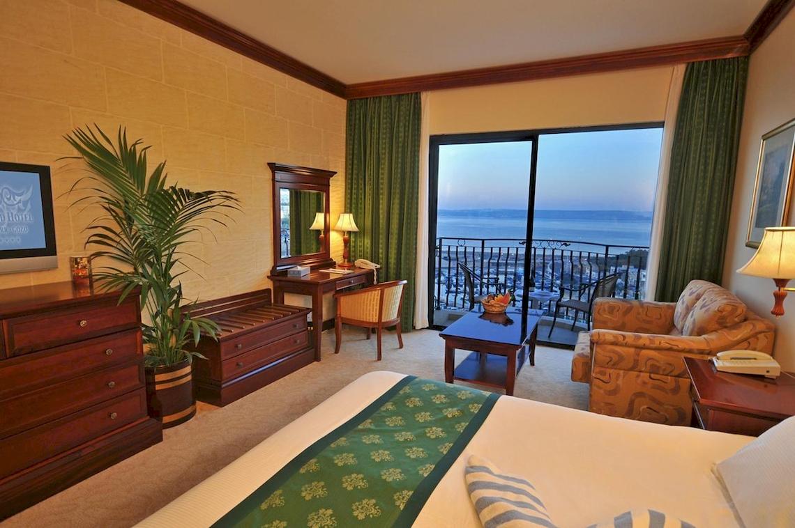 Ein elegantes Hotelzimmer im Grand Hotel Gozo mit Blick auf das Meer vom Balkon.