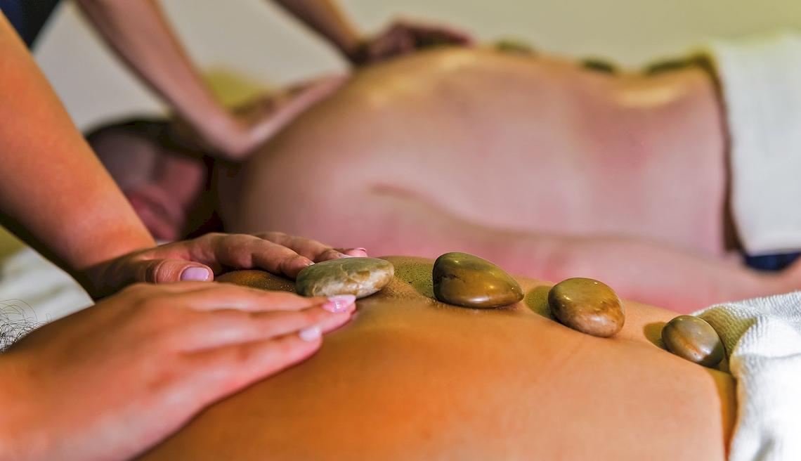 Eine Person, die eine Rückenmassage mit Steinen im Grand Hotel Gozo genießt.