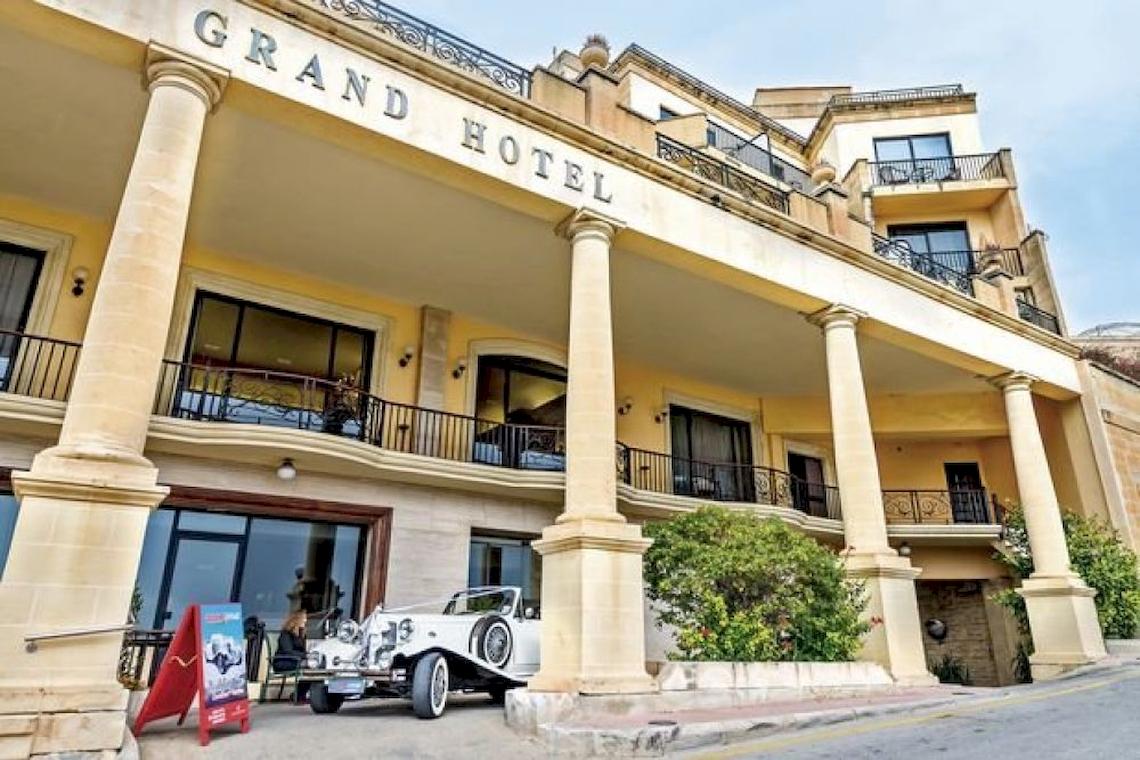 Eingang des Grand Hotel Gozo mit einem weißen Auto davor.