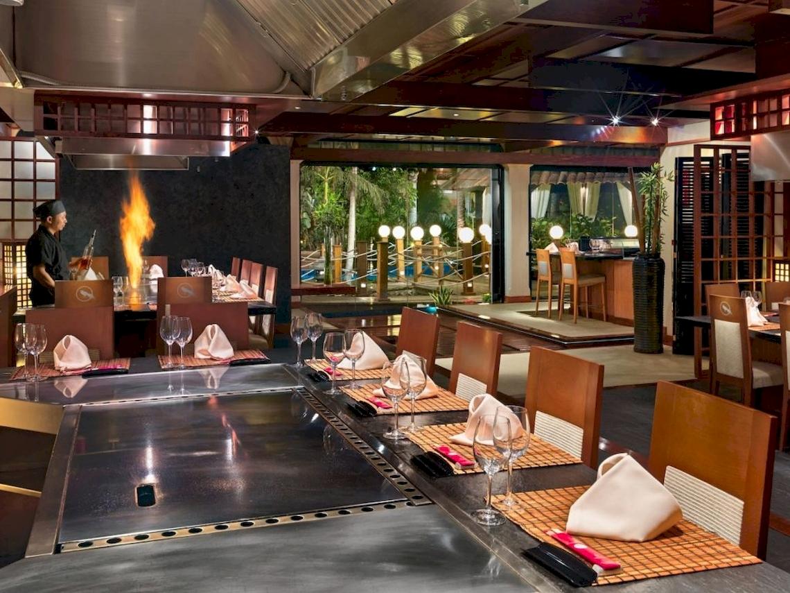 Restaurant des Secrets Bahia Real Resort & Spa mit einem Koch am Grill und gedeckten Tischen