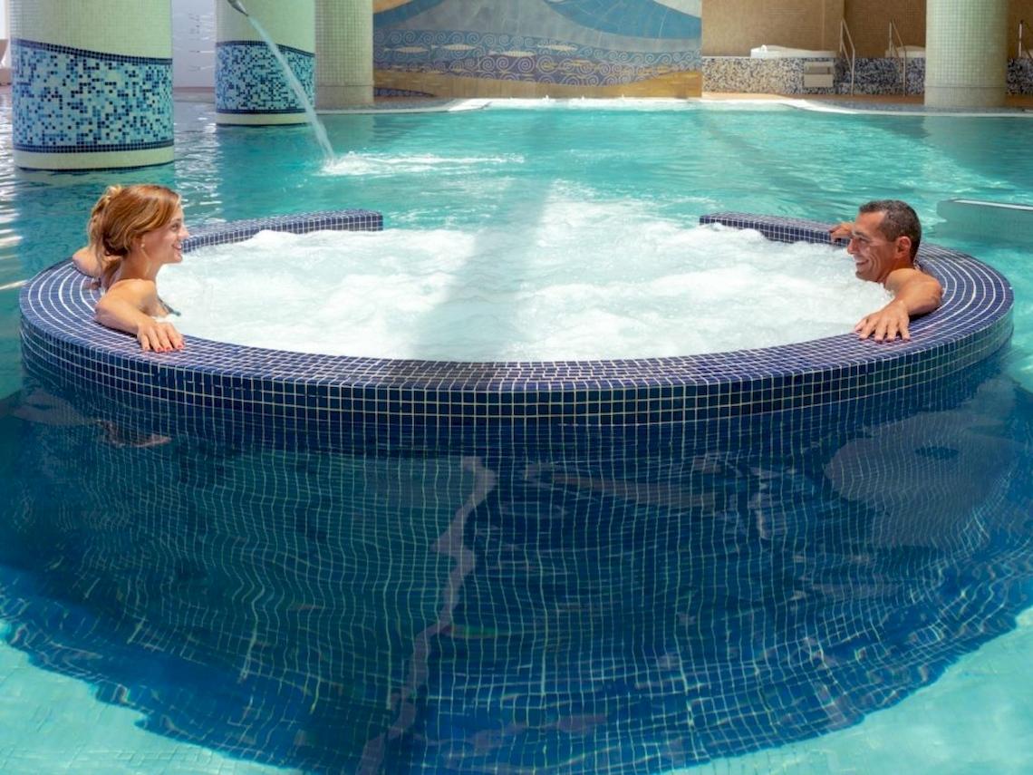 Ein Mann und eine Frau entspannen sich in einem Whirlpool im Secrets Bahia Real Resort & Spa.