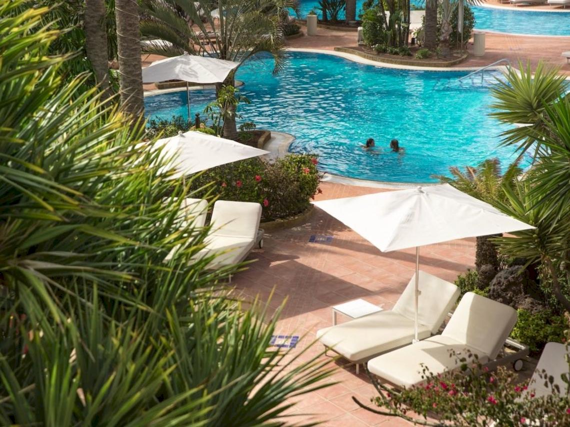 Außenpool mit Sonnenliegen und Sonnenschirmen im Secrets Bahia Real Resort & Spa.