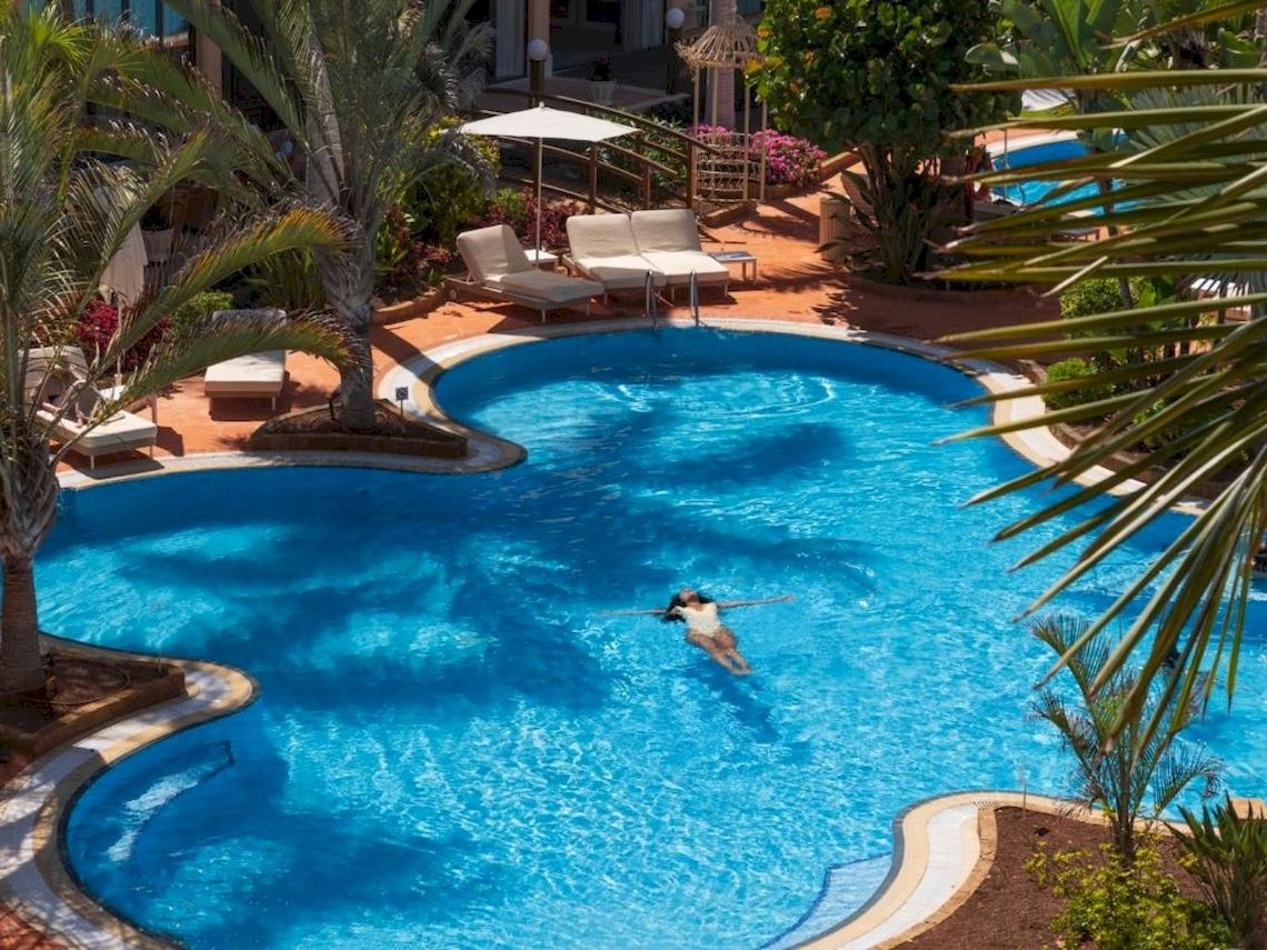 Luftaufnahme eines Schwimmbeckens im Secrets Bahia Real Resort & Spa mit einer Person, die entspannt schwimmt.
