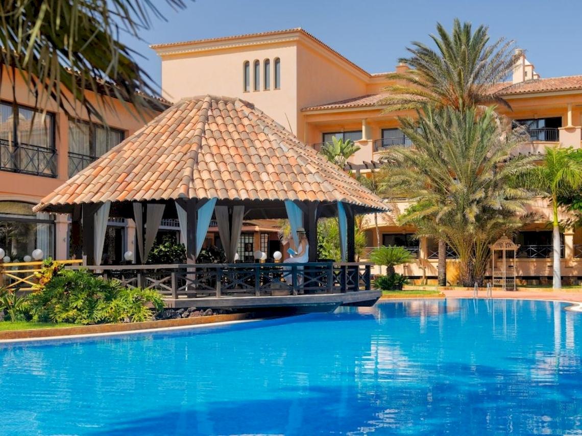 Außenpool vor dem Secrets Bahia Real Resort & Spa mit einer Frau im Himmelbett