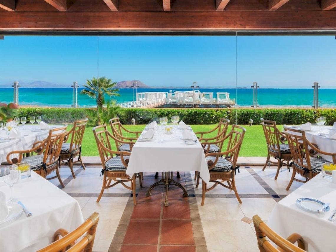 Außenbereich des Restaurants im Secrets Bahia Real Resort & Spa mit Blick auf das Meer.