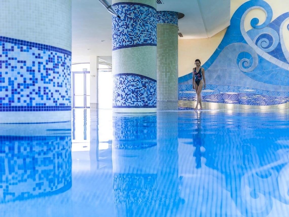 Eine Frau steht im Swimmingpool des Secrets Bahia Real Resort & Spa.