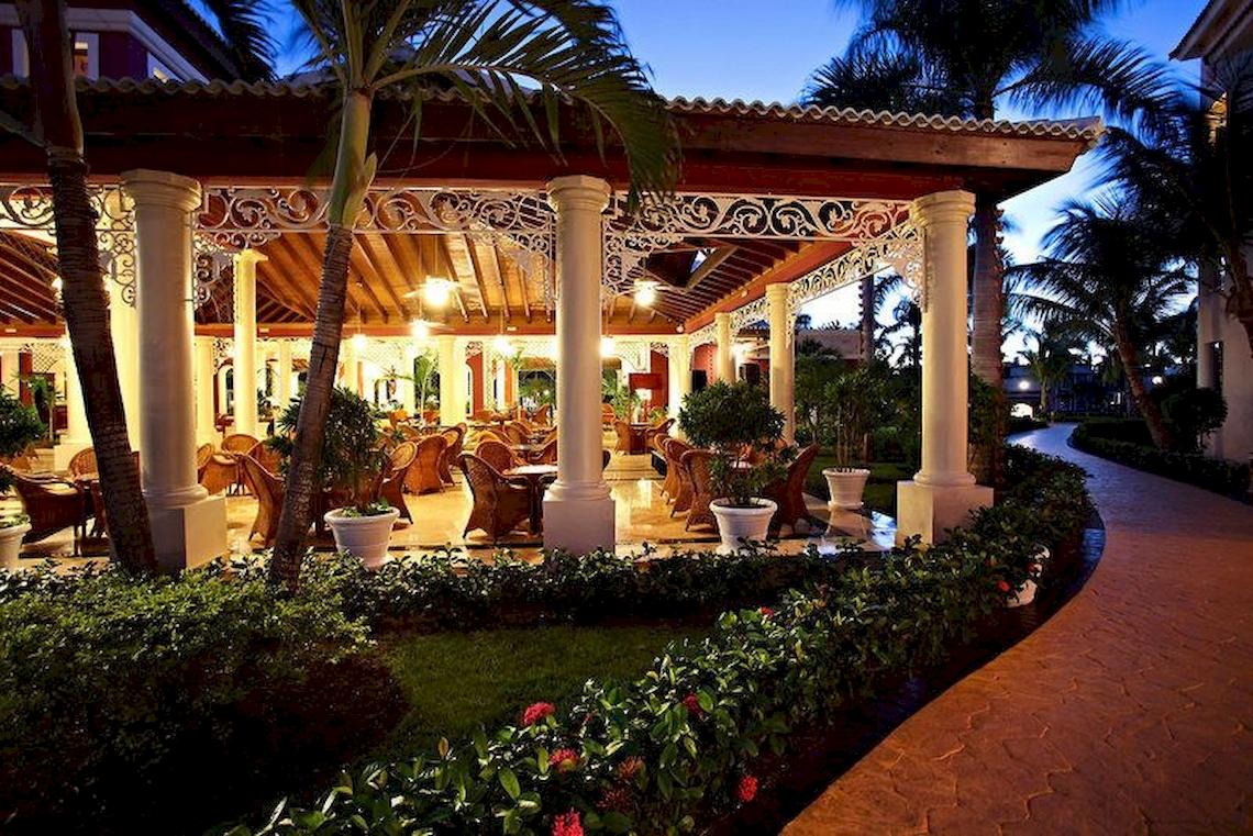 Terrasse des Bahia Principe Grand Turquesa Hotels bei Nacht mit Pflanzen und Stühlen.