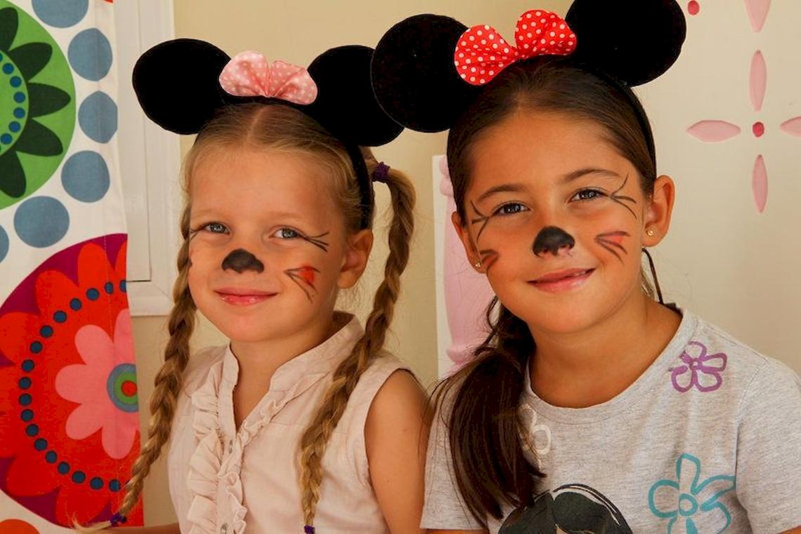 Zwei Maedchen tragen Minnie Maus Ohren und haben Katzengesichtsbemalung