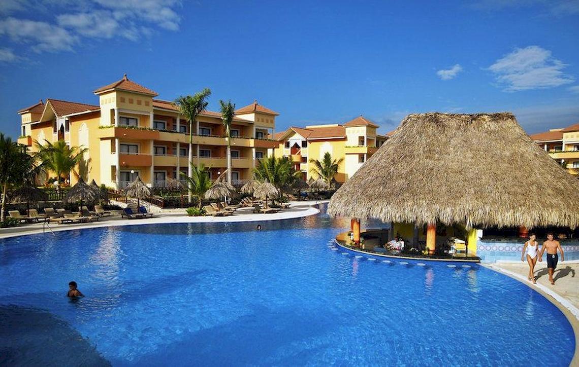 Außenbereich eines Hotels mit Pool, Bar und Palmen.