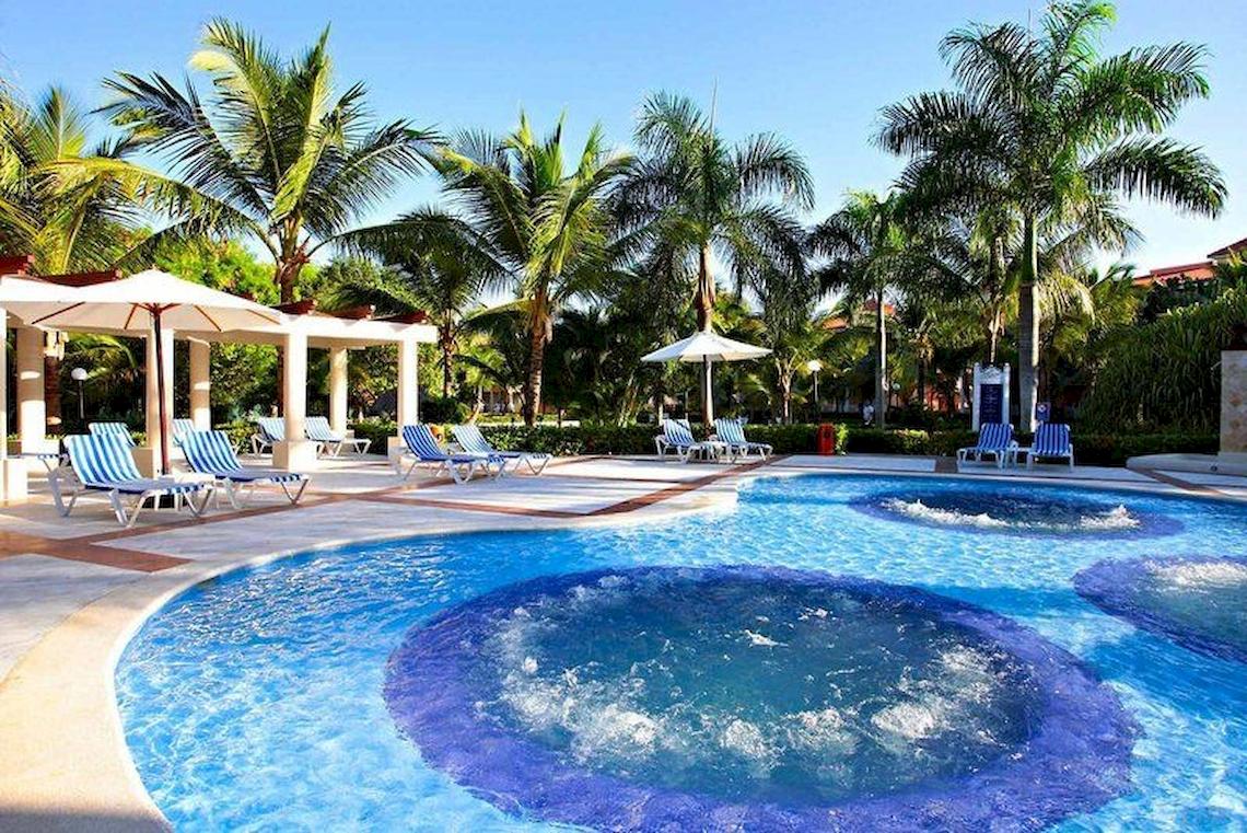 Pool im Bahia Principe Grand Turquesa Hotel mit Lounge-Liegen und Sonnenschirmen.
