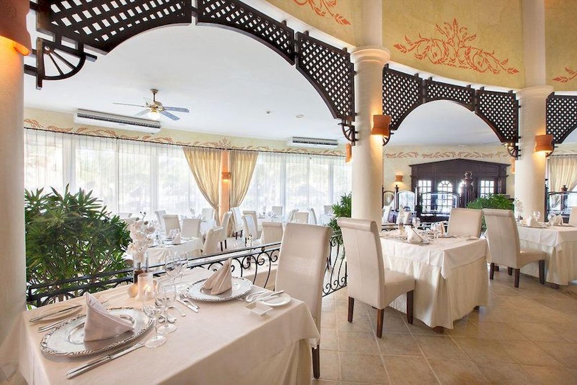 Innenansicht des Restaurants Bahia Principe Grand Turquesa mit gedeckten Tischen und Stühlen.