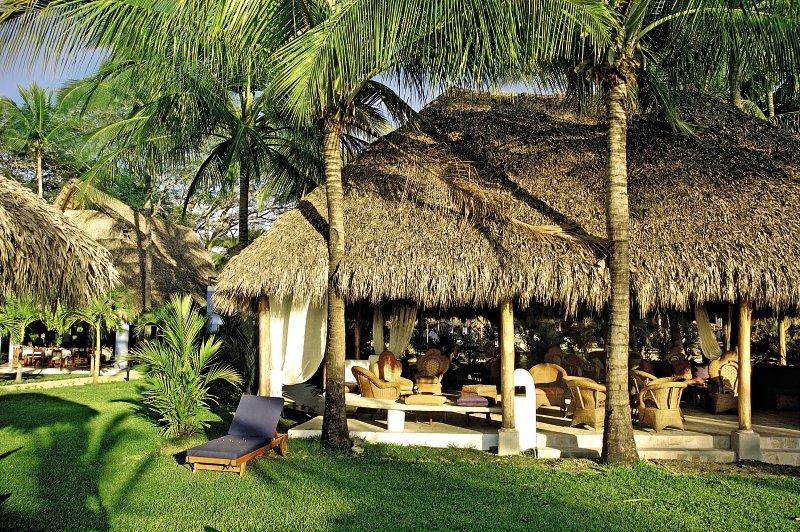 Gartenbereich des Bahia del Sol Hotels mit Palmen und Strohdächern.