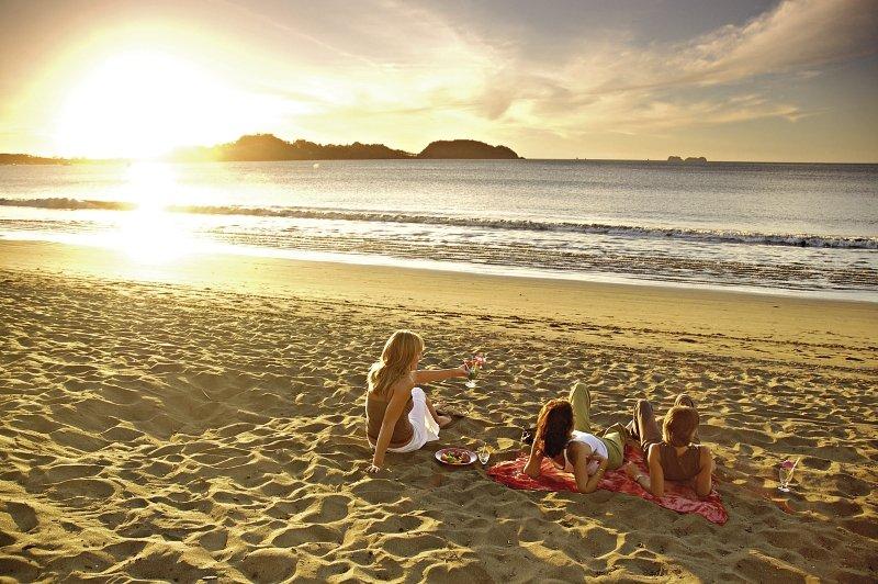 Frauen entspannen am Strand während des Sonnenuntergangs am Bahia del Sol Hotel.