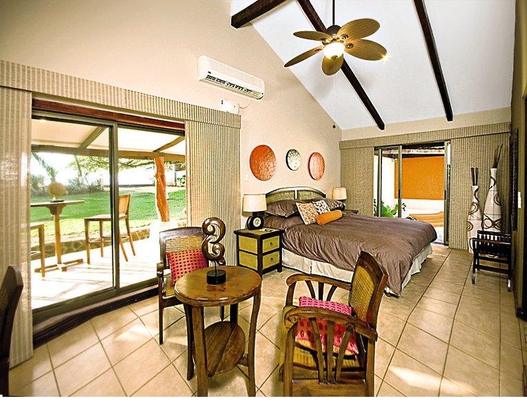 Schlafzimmer mit Terrasse im Hotel Bahia del Sol mit einem großen Bett, Deckenventilator, und Panoramafenstern.
