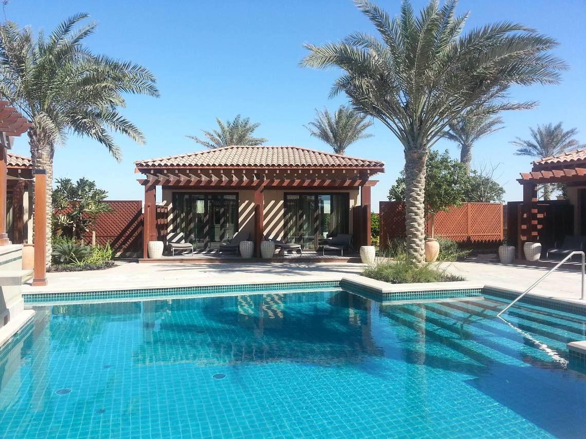 Pool des St. Regis Saadiyat Island Resorts mit umgebenden Palmen und Gebäuden